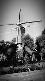 Traditional windmill by road against sky