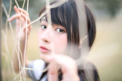 Portrait of young woman standing by sports net