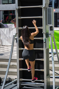 Rear view of woman climbing on ladder