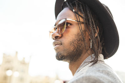 Close-up of young man standing in city against sky