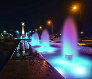 Illuminated street light against sky at night