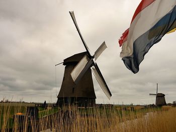 Low angle view of dutch flag against sky wirh view to traditionell windmills