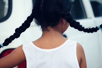 Rear view of girl with pigtails against car