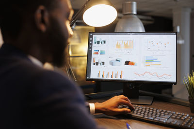 Rear view of man using laptop at office