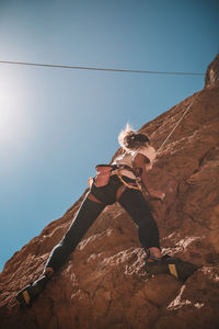 Low angle view of a woman climbing the red rocks of todgha in the moroccan desert