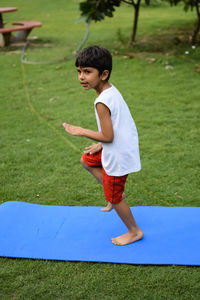 Asian smart kid doing yoga pose in the society park outdoor, children's yoga pose.