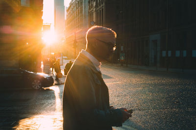 Man on city street against bright sun during sunset