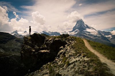 Man standing on mountain against cloudy sky