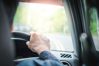 Midsection of man seen through car window