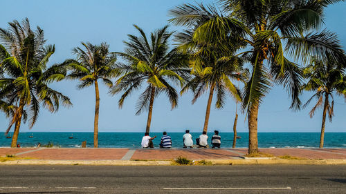 Rear view of men crouching on promenade against sky