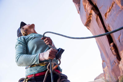 A woman belaying her climbing partner in the desert.