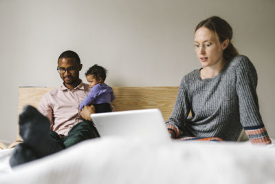 Young woman using phone while sitting on laptop