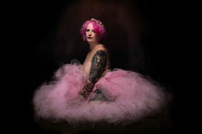 Young woman with pink hair against black background