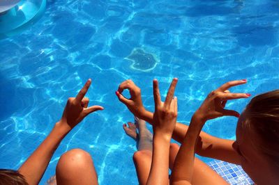 High angle view of girls gesturing while sitting in swimming pool