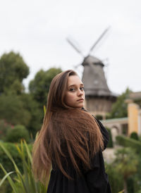 Portrait of young woman looking away against sky