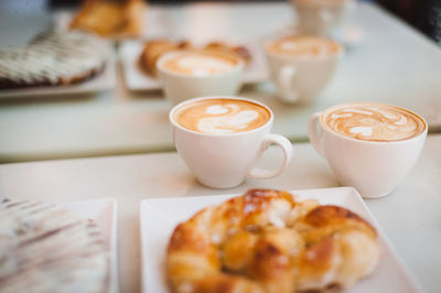 High angle view of cappuccinos with croissants served on table