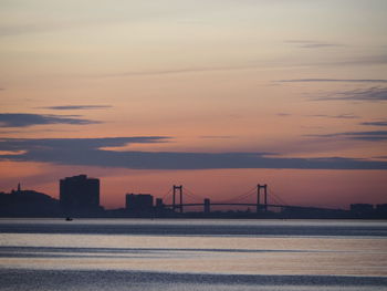 Scenic view of suspension bridge over sea against sky during sunset