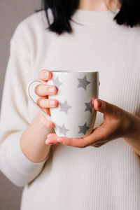 The girl in the cozy clothes holding a cup of coffee. female hands with hot drink