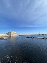 Sea by buildings against blue sky