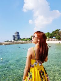 Beautiful woman standing by sea against sky