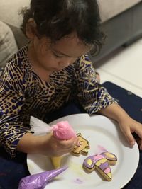 High angle view of girl icing cookies at table