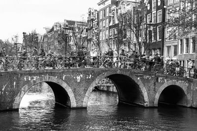 Arch bridge over river in city against sky