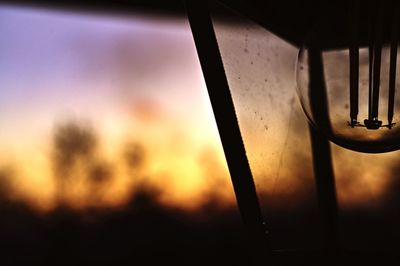 Close-up of glass window against orange sky