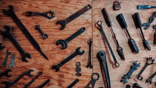 Black tools arranged on wooden wall