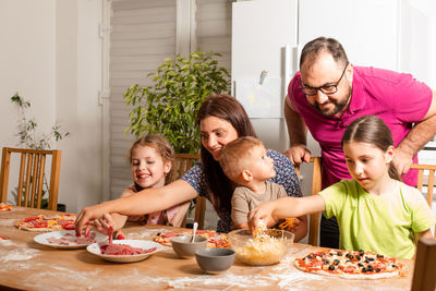 Cheerful kids preparing food with parent at home