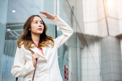 Portrait of young woman standing against wall