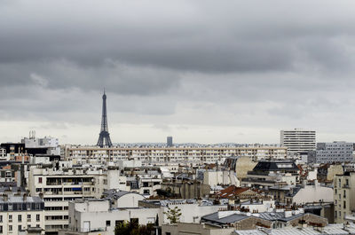 Cityscape and eiffel tower against cloudy sky