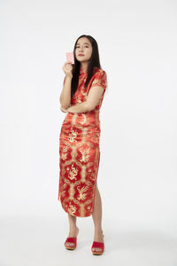 Portrait of young woman standing against white background