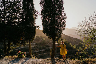 Girl standing by plants against sky