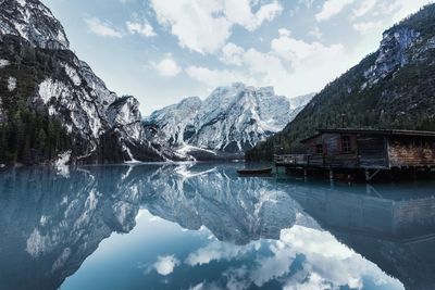 Stilt house in lake with mountains reflection against sky