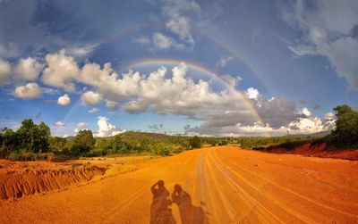 Panoramic view of road amidst field against sky