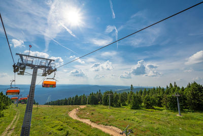 Overhead cable car on road against sky