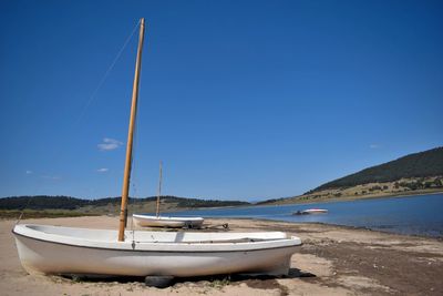 Sailboats moored on sea against clear blue sky