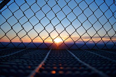 Chainlink fence against sky during sunset