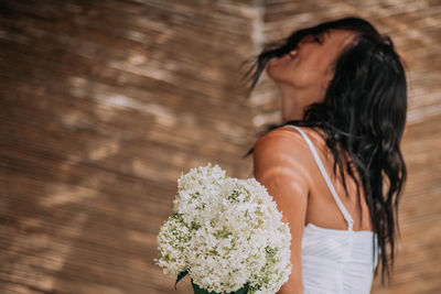 Midsection of woman standing by flowering plant