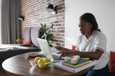 Ethnic student using laptop at home