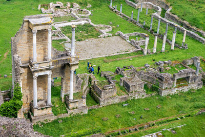 Tourists group visiting remains or ruin of ancient roman amphitheatre in volterra, tuscany, italy