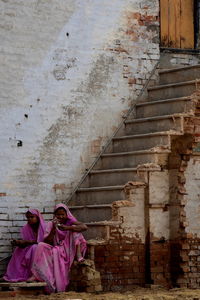 Woman sitting on staircase of building