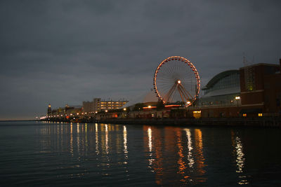 Illuminated ferris wheel at navy pier in sea against sky