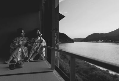 People sitting by lake against sky