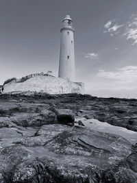 Lighthouse by sea against sky