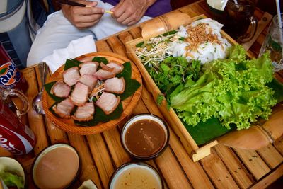 Midsection of man sitting by food at table