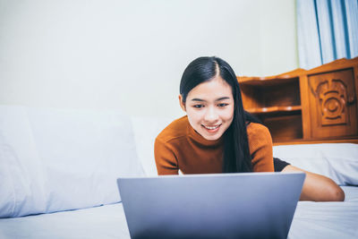 Portrait of smiling young woman using mobile phone at home