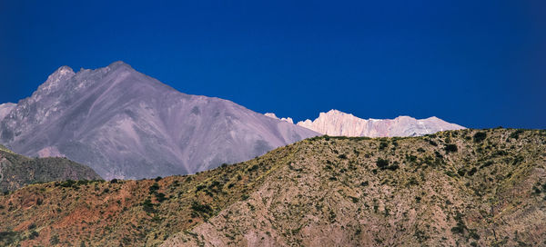 Scenic view of snowcapped mountains against clear blue sky