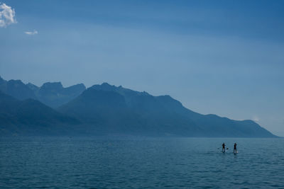 People on mountain by sea against sky