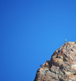 Low angle view of people climbing rocky mountain